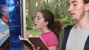 a teen boy and girl  singing hymns in church (focus is on girl)